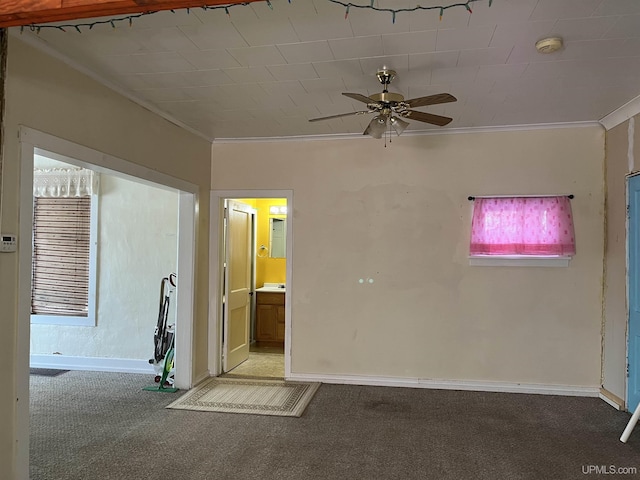 spare room featuring carpet flooring, baseboards, a ceiling fan, and crown molding