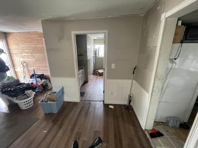 corridor featuring a textured ceiling, wood finished floors, and wainscoting