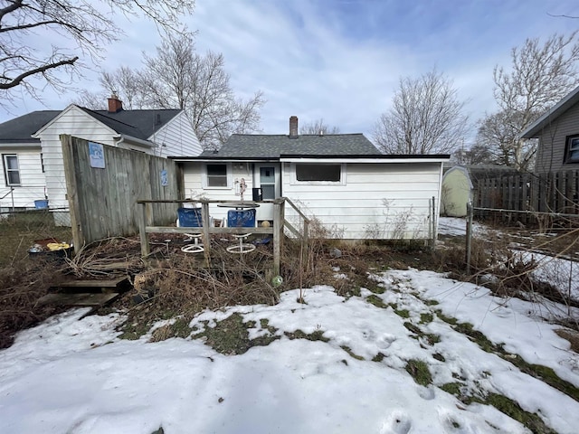 snow covered property featuring fence and a chimney