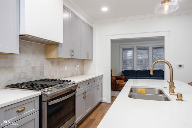 kitchen featuring gas range, gray cabinetry, crown molding, and a sink