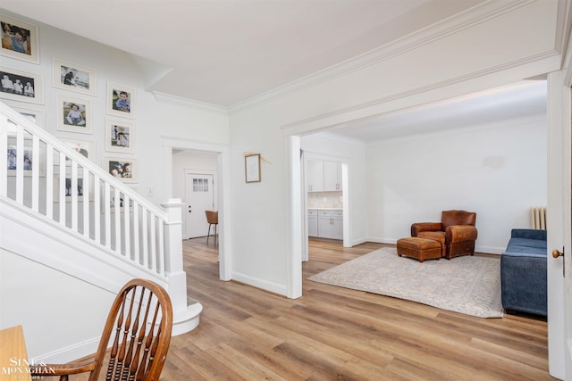 interior space with light wood-type flooring, stairway, radiator, crown molding, and baseboards