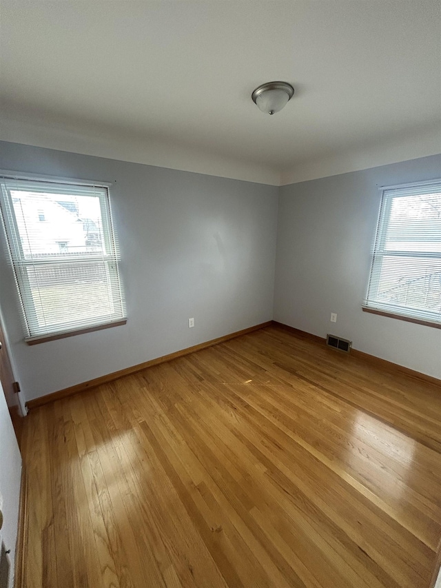 spare room featuring baseboards, visible vents, and light wood finished floors