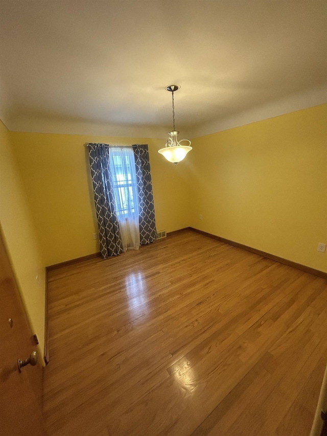 unfurnished room featuring visible vents, baseboards, and wood finished floors