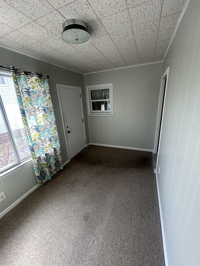 empty room with baseboards and dark colored carpet