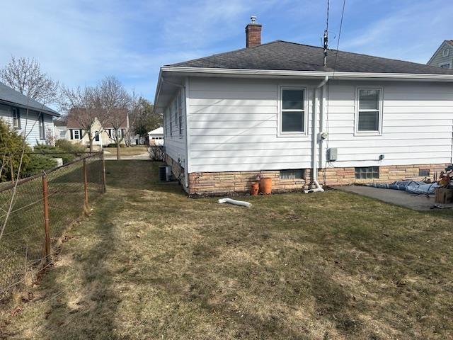 rear view of property featuring crawl space, a yard, fence, and a chimney