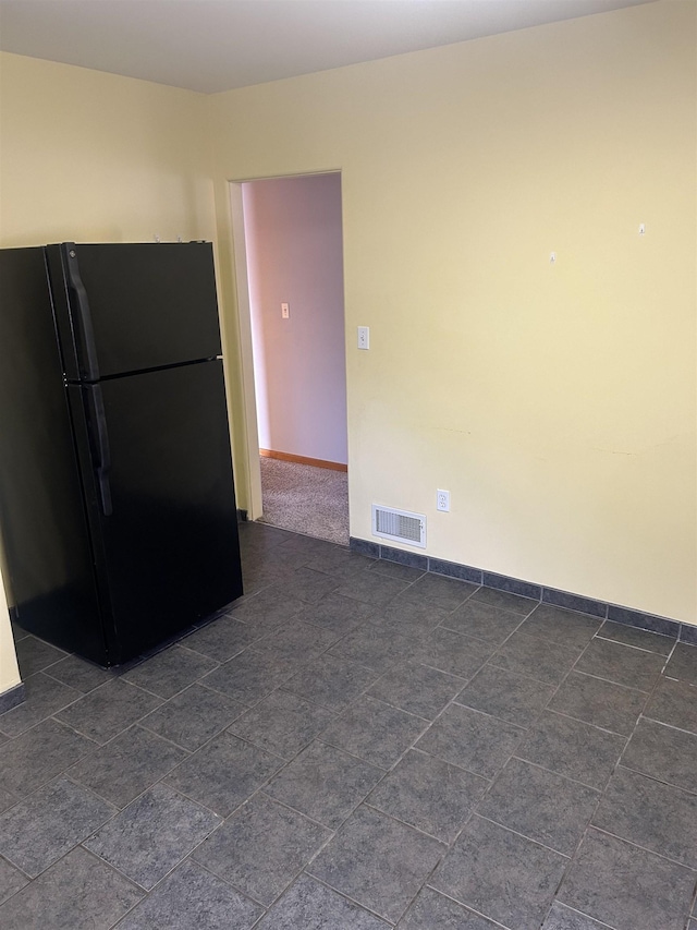 kitchen featuring baseboards, visible vents, and freestanding refrigerator