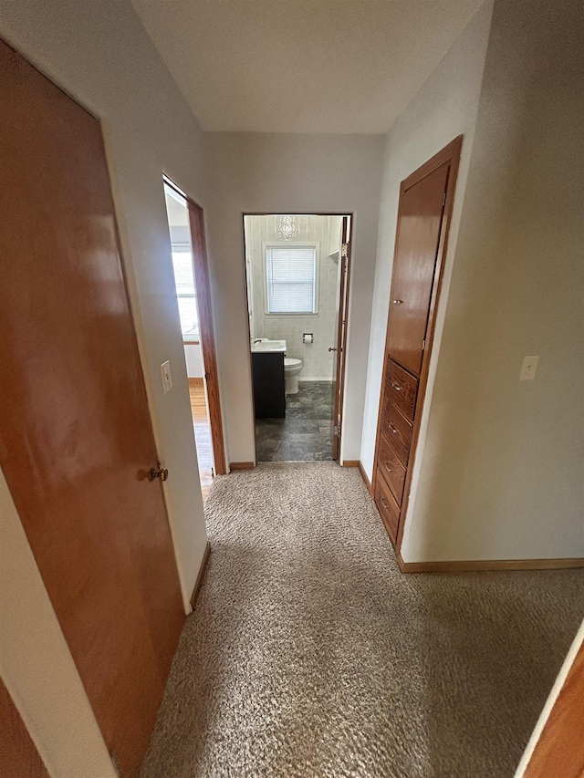 corridor with baseboards and carpet