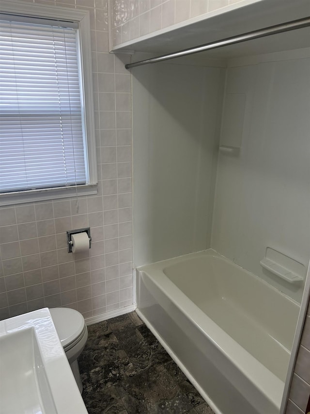 full bathroom featuring tile walls, toilet, and a healthy amount of sunlight