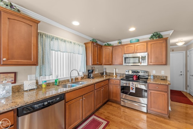 kitchen with light stone countertops, ornamental molding, light wood-style floors, stainless steel appliances, and a sink