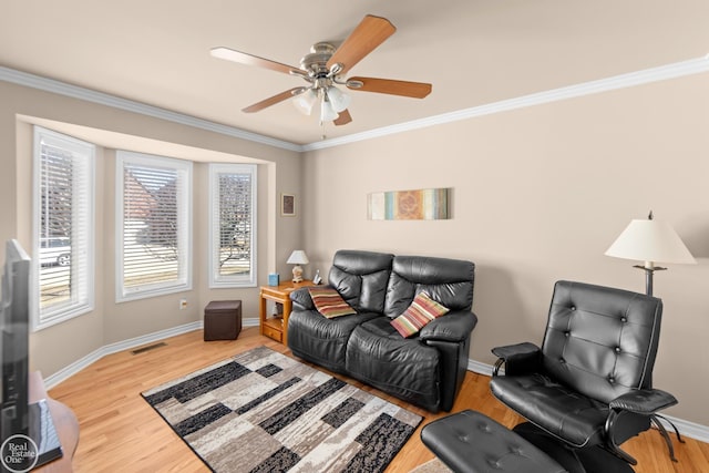 living area with crown molding, wood finished floors, baseboards, and ceiling fan