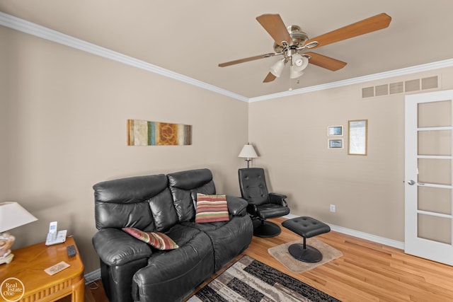 living room with a ceiling fan, wood finished floors, visible vents, baseboards, and crown molding