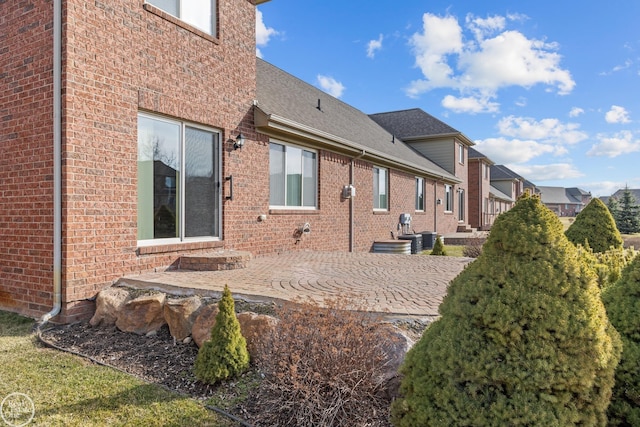 back of house featuring brick siding and a patio area