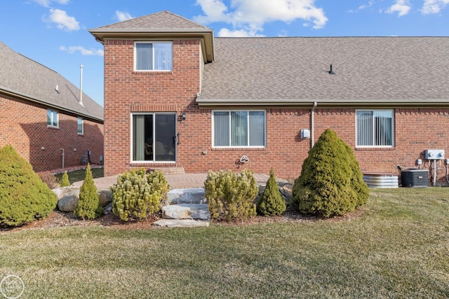 rear view of property featuring a patio, brick siding, roof with shingles, and a lawn