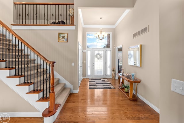 foyer featuring visible vents, baseboards, wood finished floors, and a chandelier