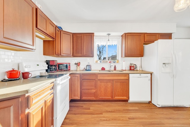 kitchen featuring white appliances, light countertops, light wood-type flooring, and a sink