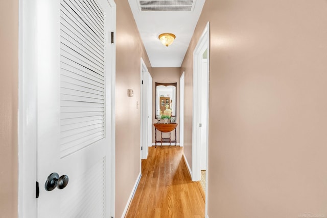 hallway with visible vents, baseboards, and light wood-style floors