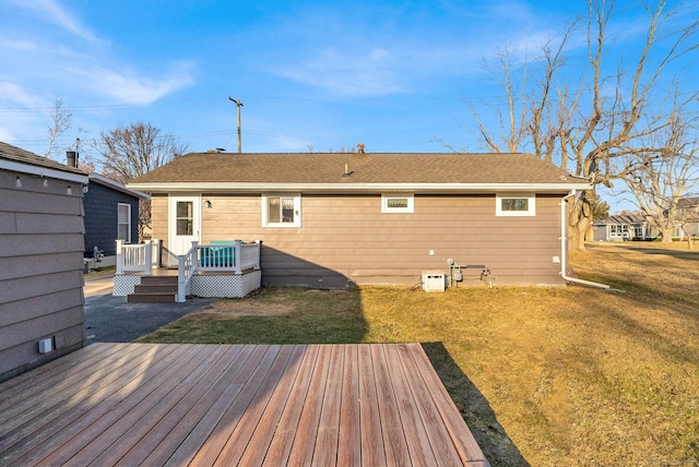 rear view of house featuring a yard, a wooden deck, and a shingled roof