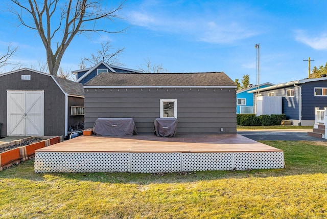 wooden terrace with fence, a shed, a lawn, an outbuilding, and area for grilling