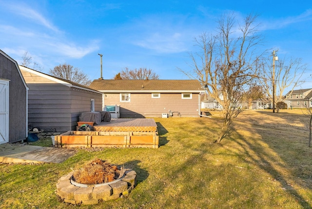 rear view of house with a deck, a yard, and an outdoor fire pit