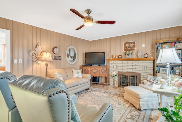 living room with a brick fireplace, ornamental molding, and a ceiling fan