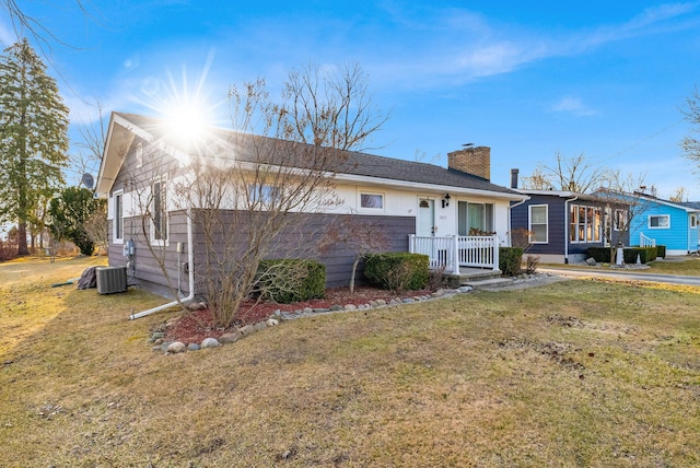 view of front of house featuring central air condition unit, a front lawn, a porch, and a chimney