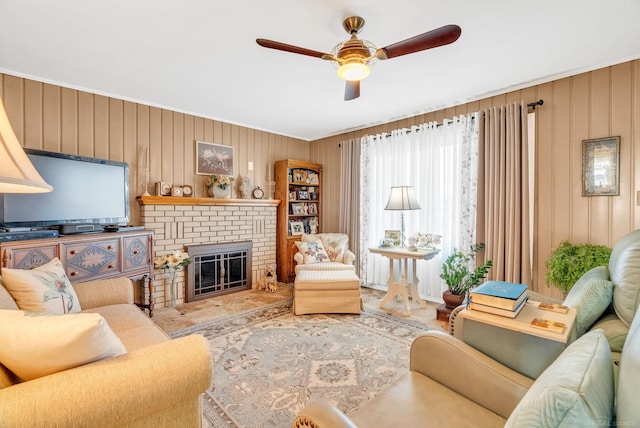 living area with wooden walls, a brick fireplace, and a ceiling fan