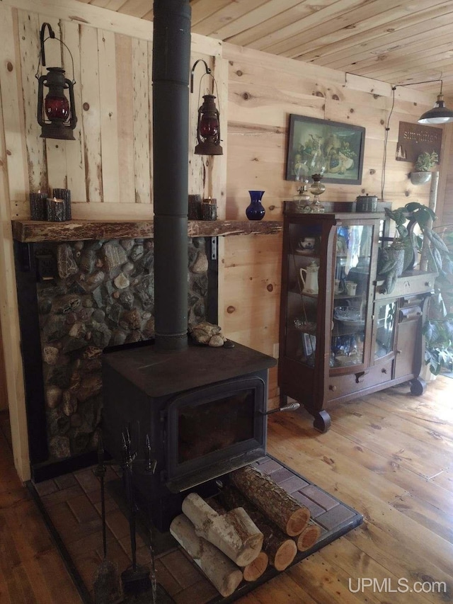 interior details with wooden ceiling, a wood stove, wood finished floors, and wood walls