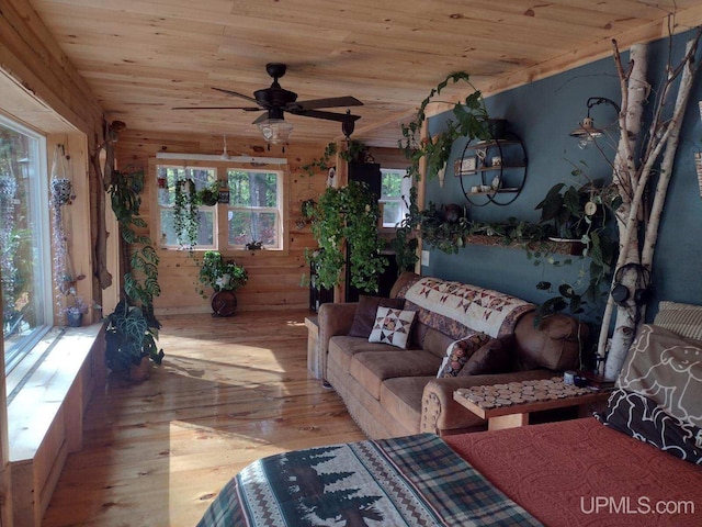 interior space featuring wood walls, wooden ceiling, a ceiling fan, and hardwood / wood-style flooring