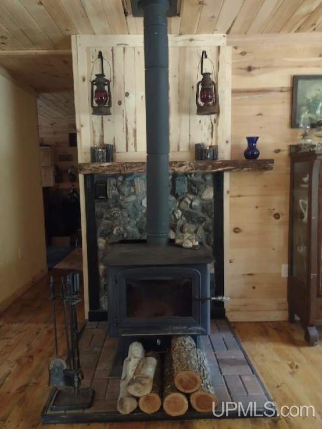 room details featuring wood finished floors, a wood stove, wood ceiling, and wood walls