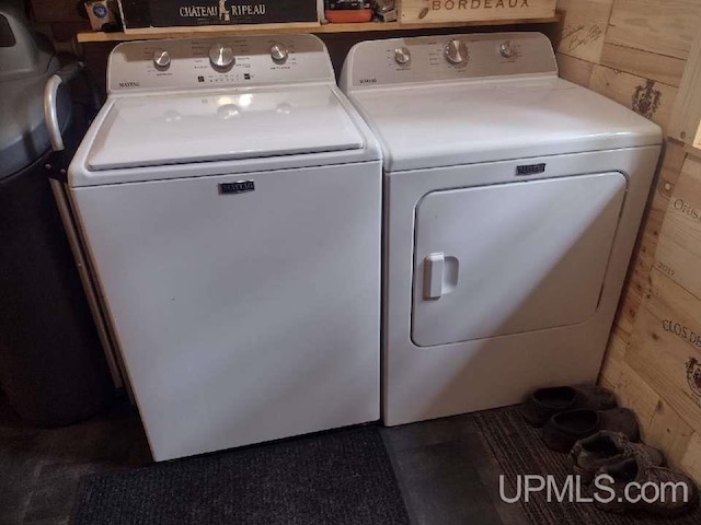 clothes washing area featuring washing machine and dryer and wood walls