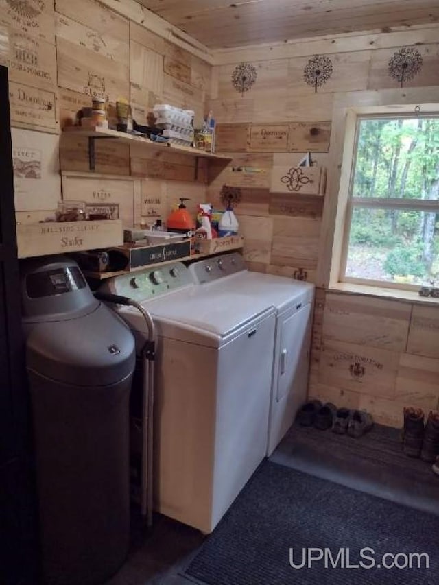 washroom with laundry area, separate washer and dryer, and wood walls