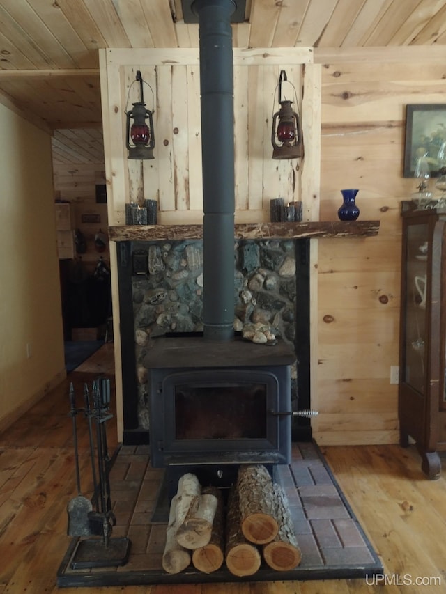 room details featuring wooden walls, wood ceiling, wood finished floors, and a wood stove