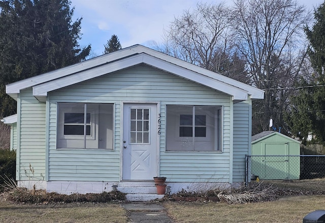 view of front of home featuring entry steps, an outbuilding, fence, and a shed