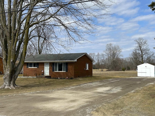 view of property exterior with brick siding, a garage, driveway, and an outdoor structure