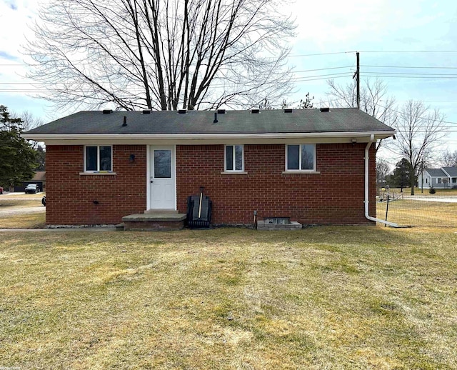 rear view of property featuring brick siding and a yard