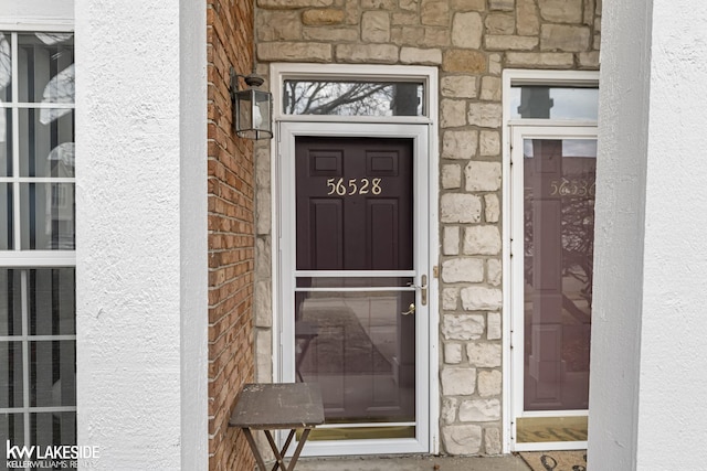 doorway to property featuring brick siding, stone siding, and stucco siding