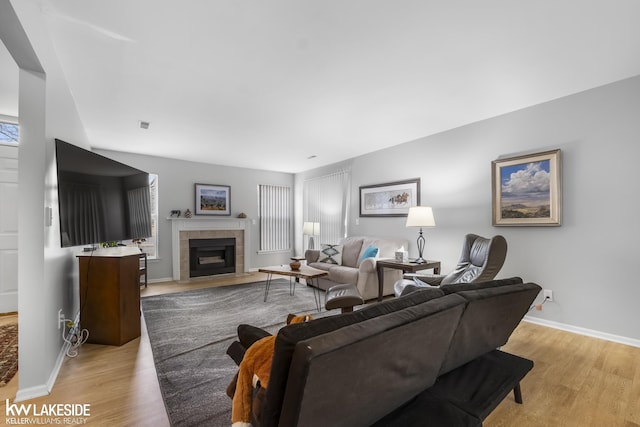 living room with a fireplace, baseboards, and light wood-style floors