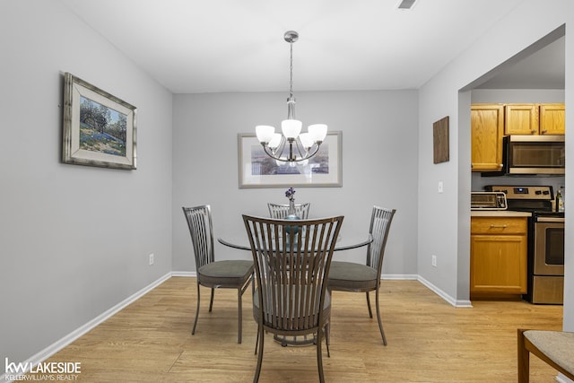 dining room featuring light wood-type flooring, baseboards, an inviting chandelier, and visible vents