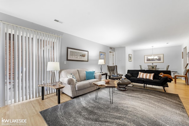 living area with visible vents, a notable chandelier, and wood finished floors