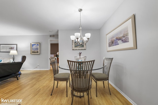 dining room with a chandelier, baseboards, and wood finished floors