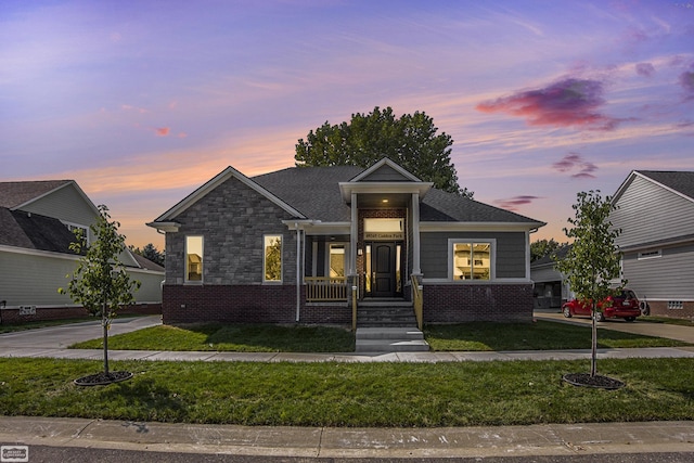 view of front facade with a front yard, brick siding, and stone siding