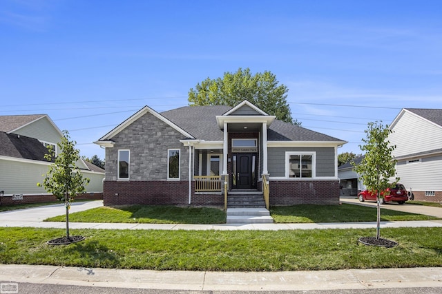 bungalow-style home with stone siding, brick siding, roof with shingles, and a front yard