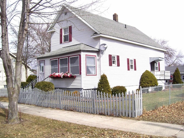 view of front of home featuring a shingled roof, a fenced front yard, and a chimney