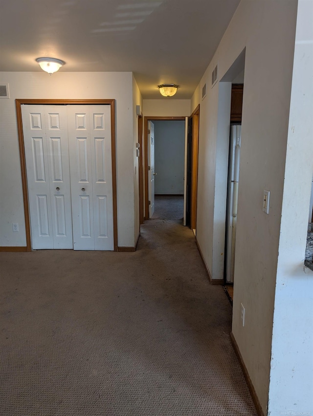 corridor with visible vents, baseboards, and light colored carpet