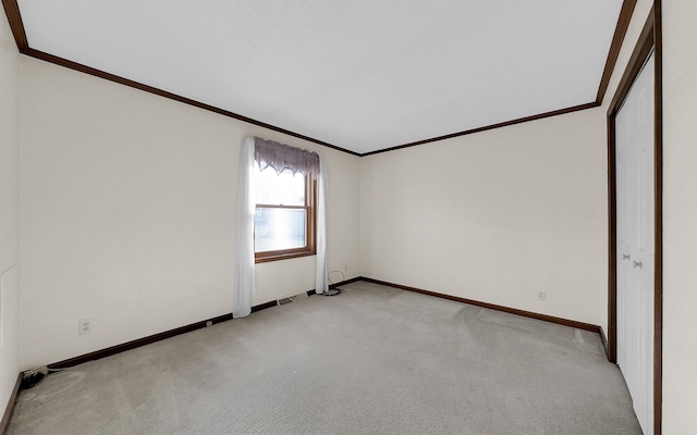 spare room featuring baseboards, light colored carpet, and crown molding