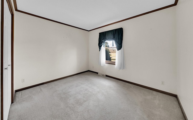 empty room featuring visible vents, baseboards, crown molding, and carpet