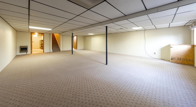 finished basement featuring heating unit, stairway, a drop ceiling, and carpet floors