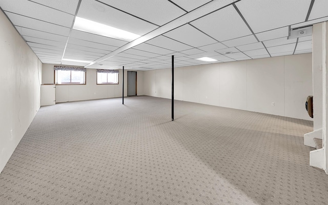 basement featuring a paneled ceiling and carpet floors