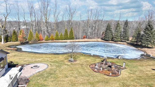 view of pool with a lawn, a forest view, and an outdoor fire pit