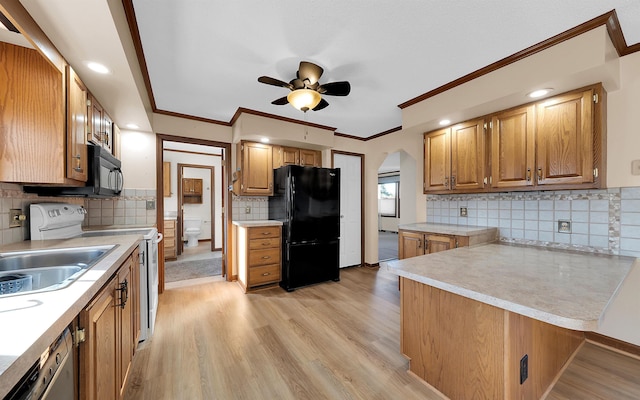 kitchen featuring light wood-style flooring, a peninsula, black appliances, and light countertops